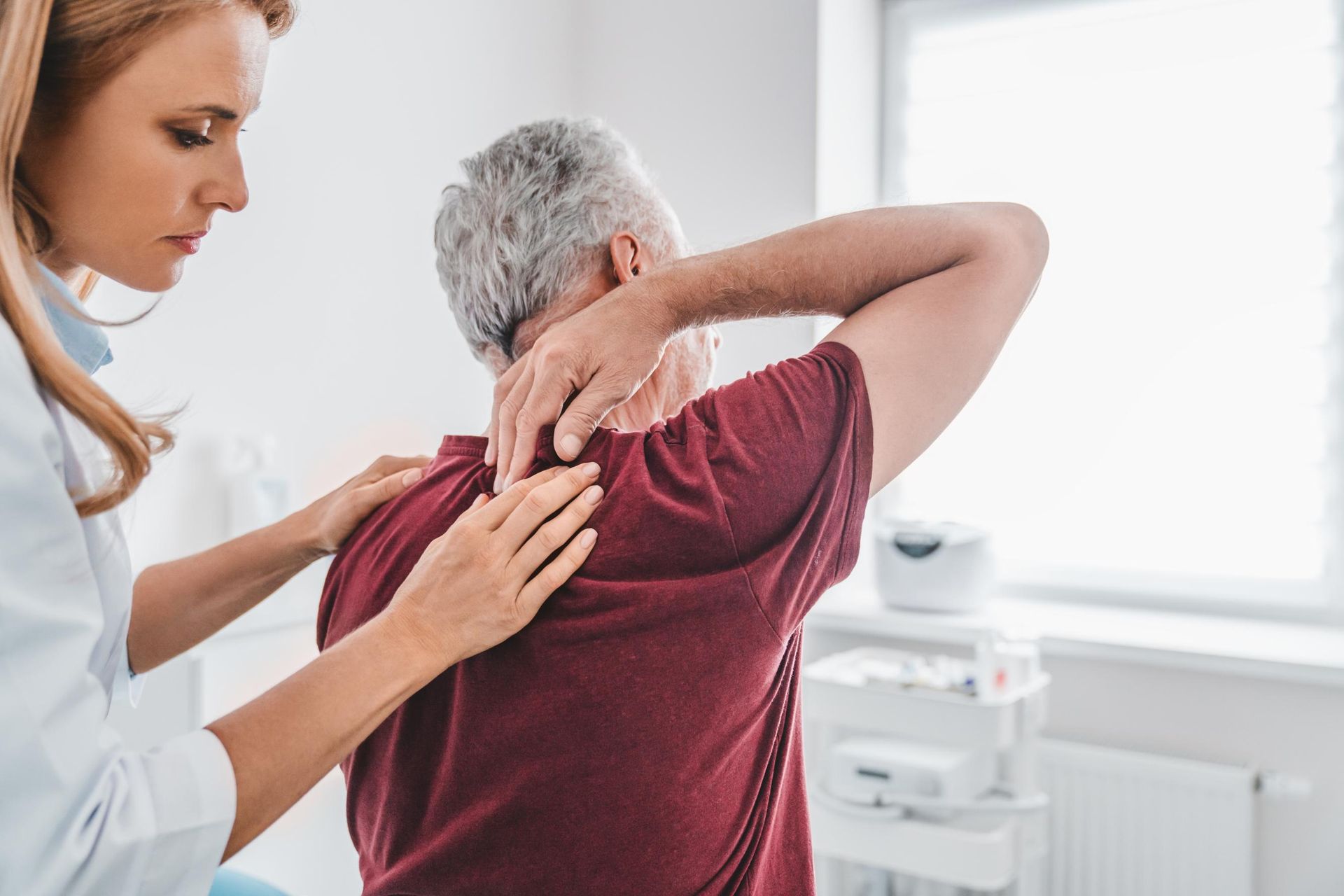 Caregiver helping a patient stretch shoulder in a bright clinic room