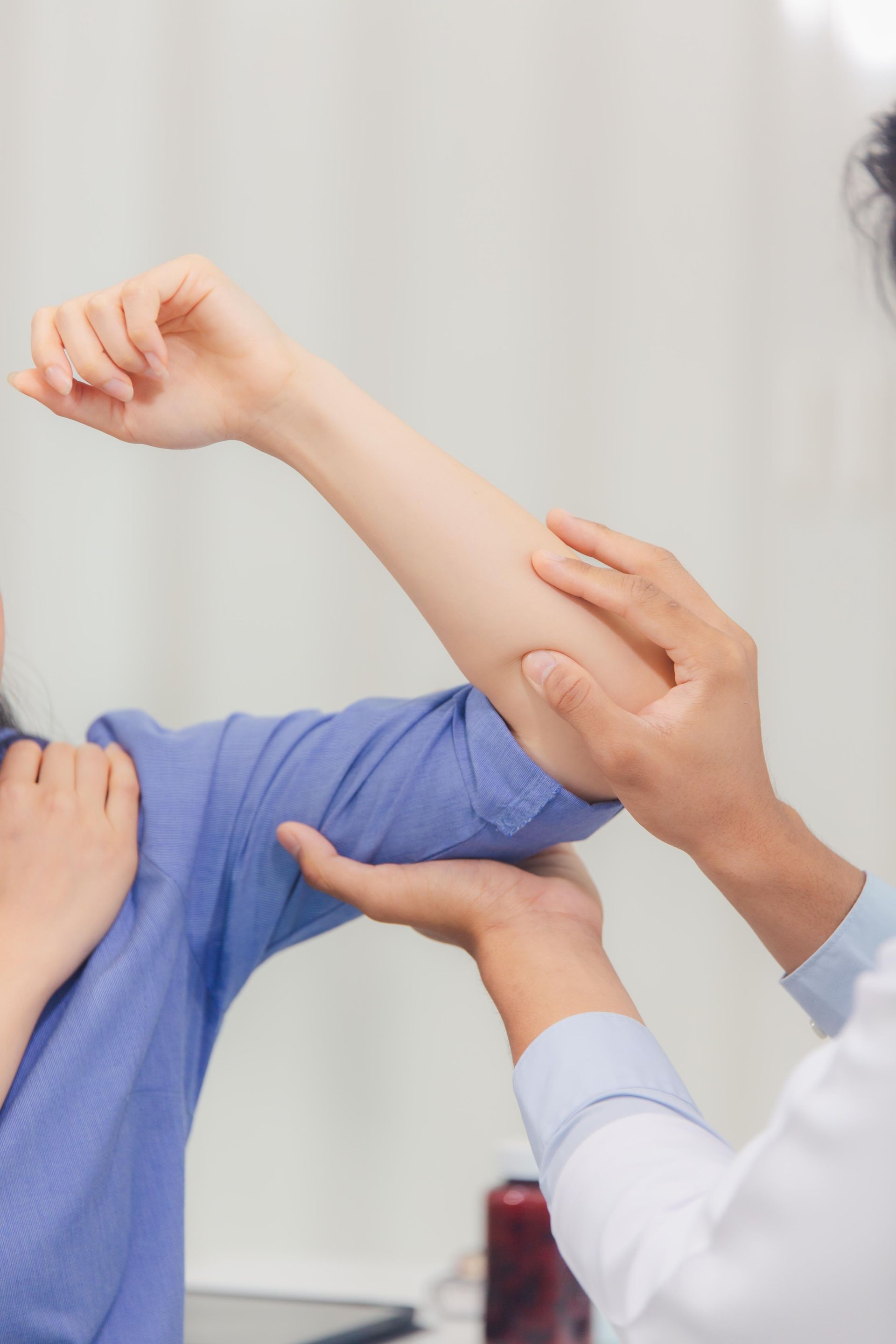 Healthcare worker examining a patient’s bent arm in a clinical setting