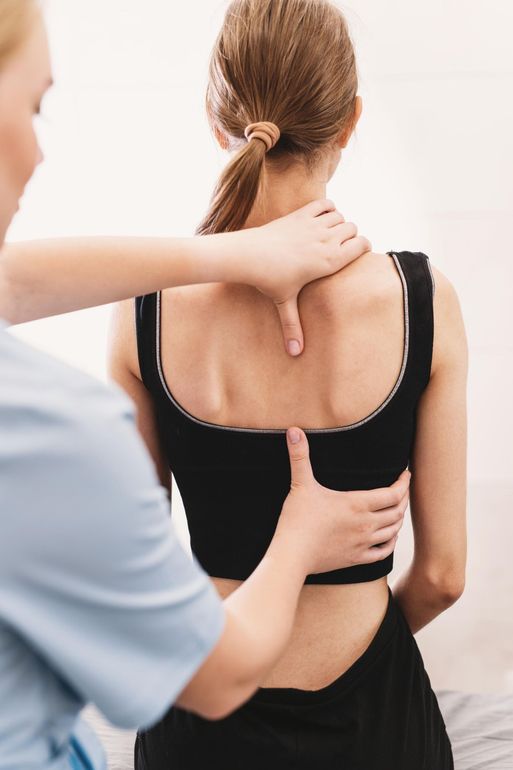 Massage therapist pressing a woman’s upper back and neck during a treatment session