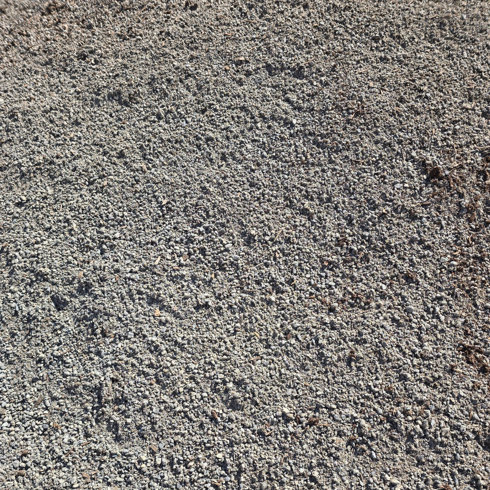 Close-up of a gray gravel or pebble surface with a small brown leaf on the right edge