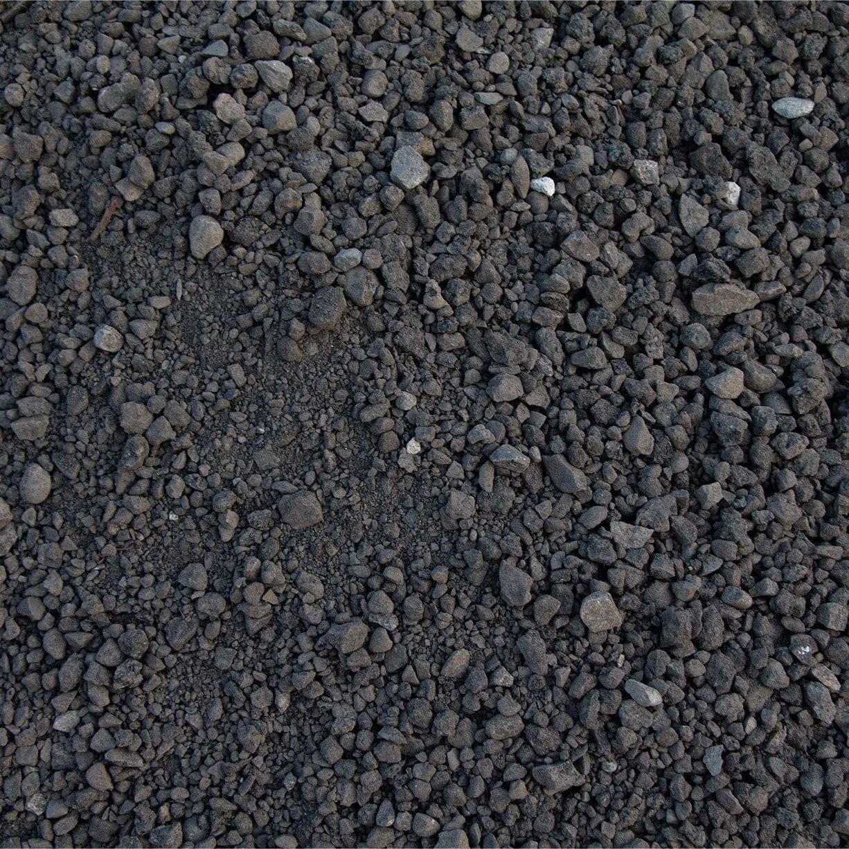 Dark gray gravel stones covering the ground, with a rough, pebbled texture