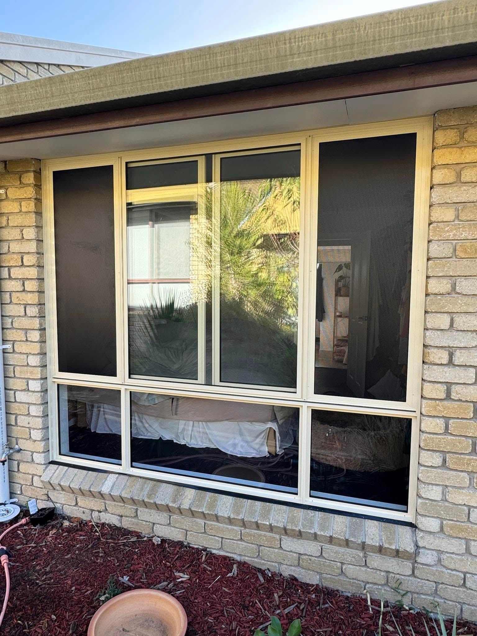 Broken window with cracked panes in a brick house exterior under a roof overhang — Channel Glazing In Electrona, TAS