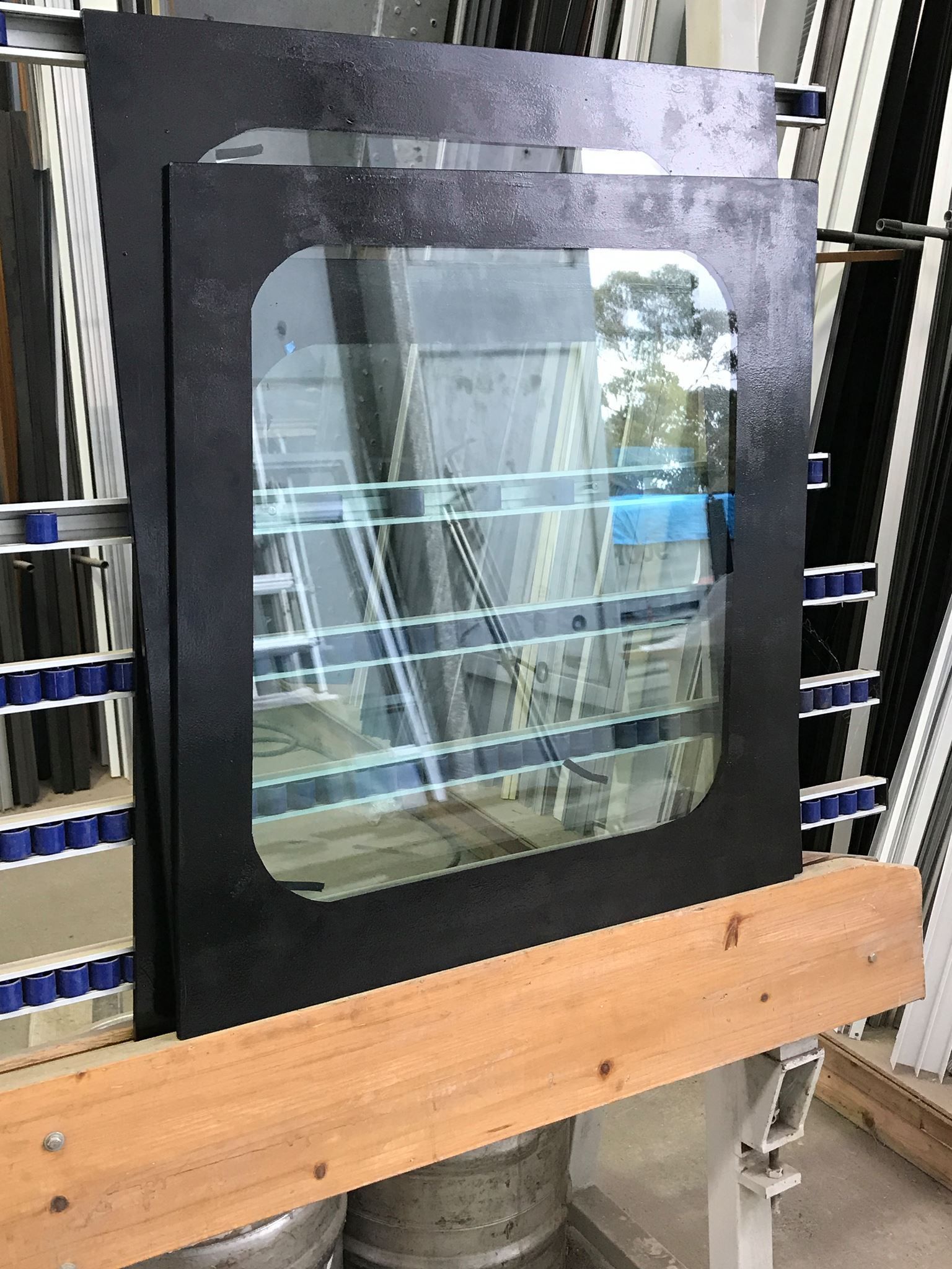 Black windowed door panel leaning on a shelf in a workshop. — Channel Glazing In Electrona, TAS