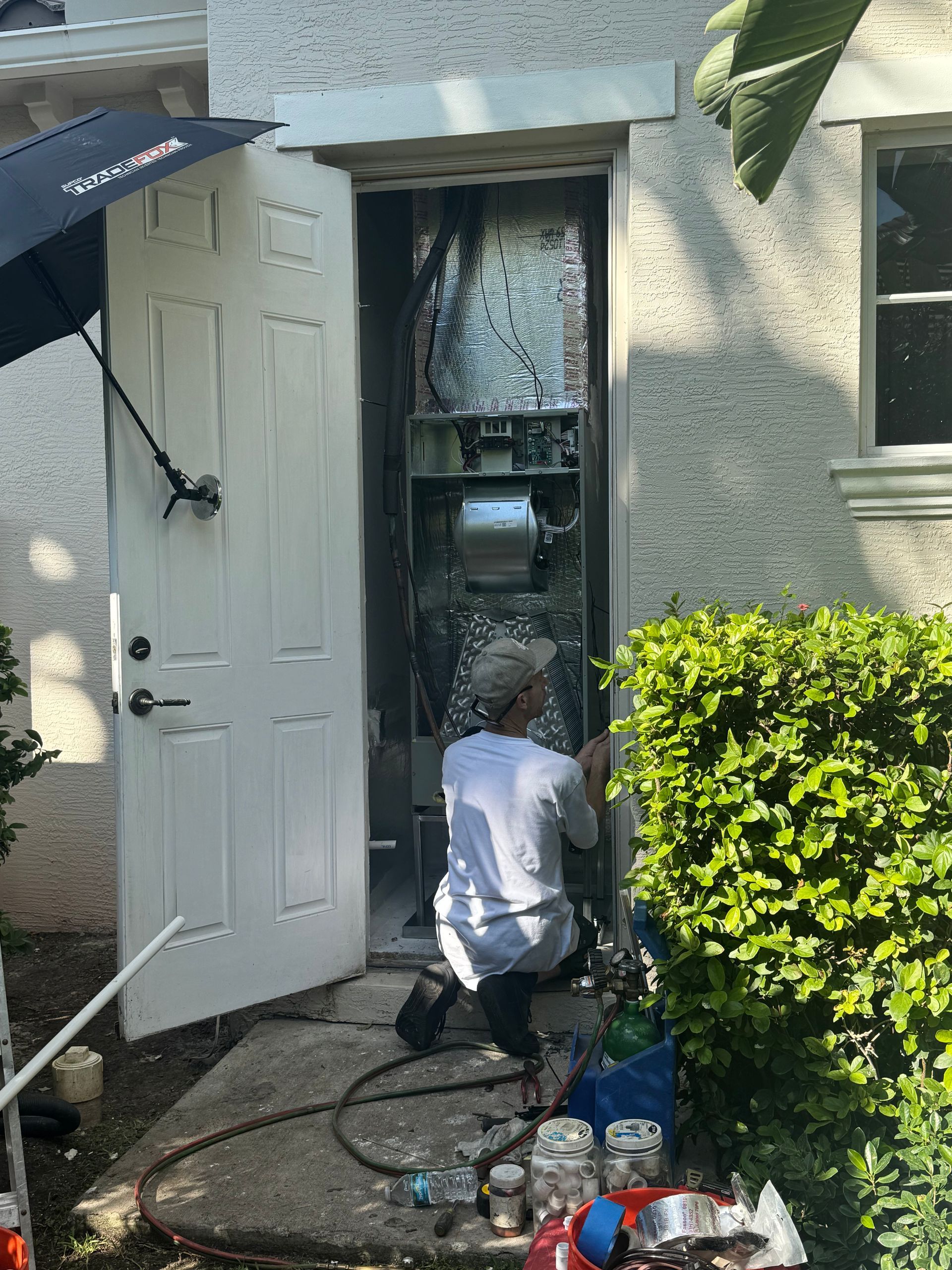 Person pressure-washing a front door and entryway beside a white house with an awning.