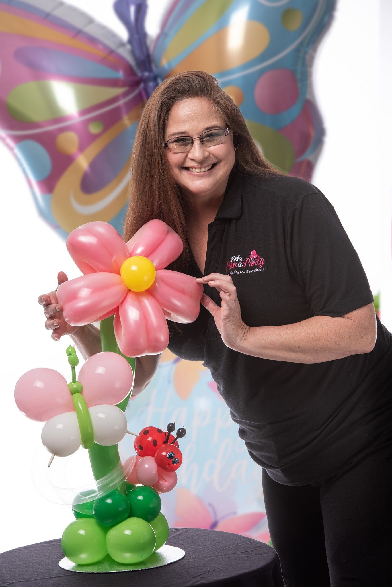 A woman is standing next to a flower made out of balloons.