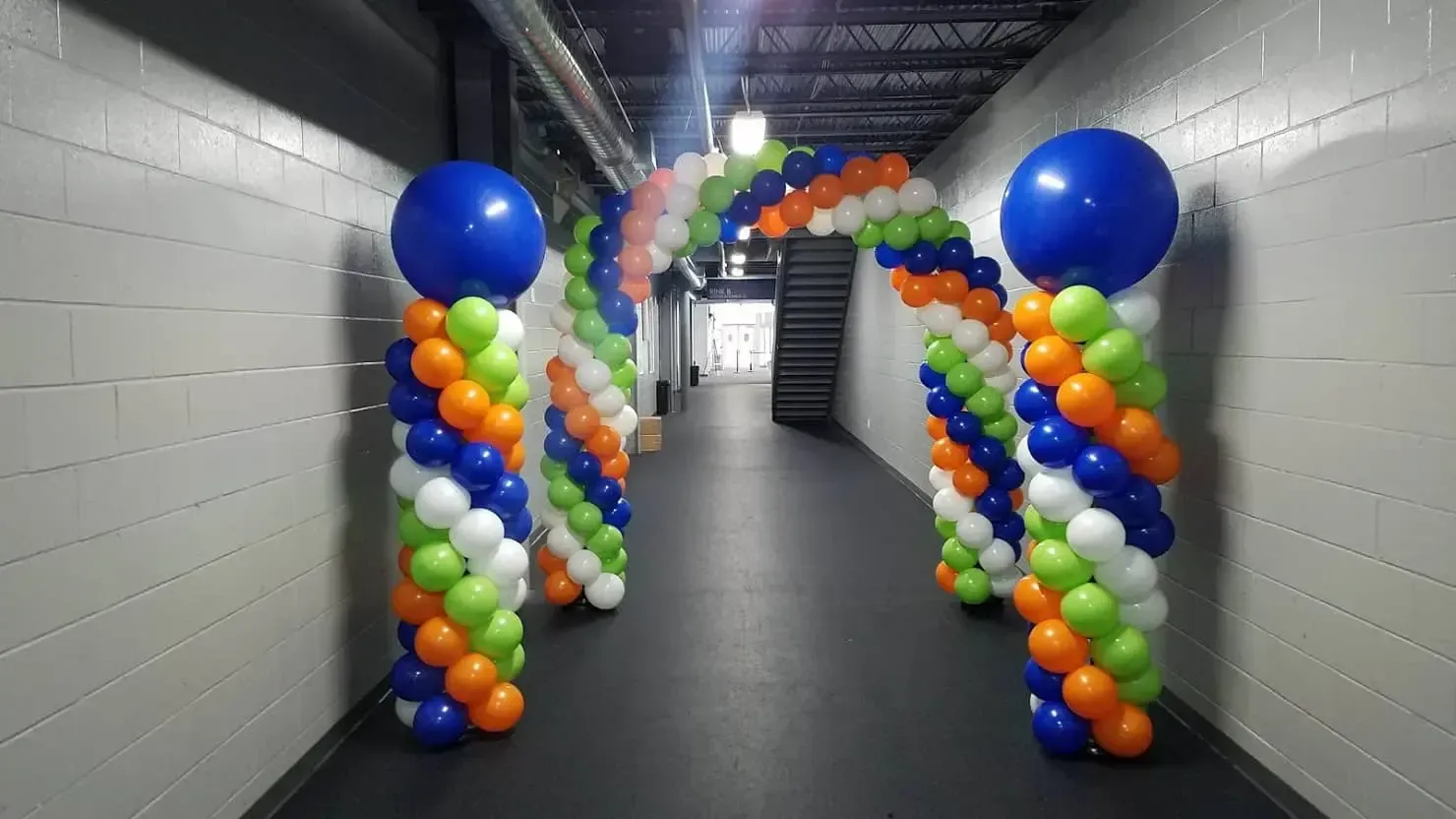 A hallway filled with colorful balloons and columns.