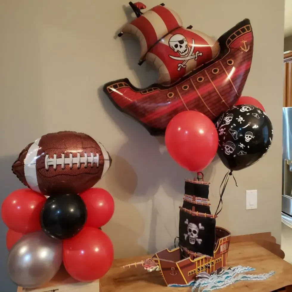 A pirate ship is surrounded by red and black balloons