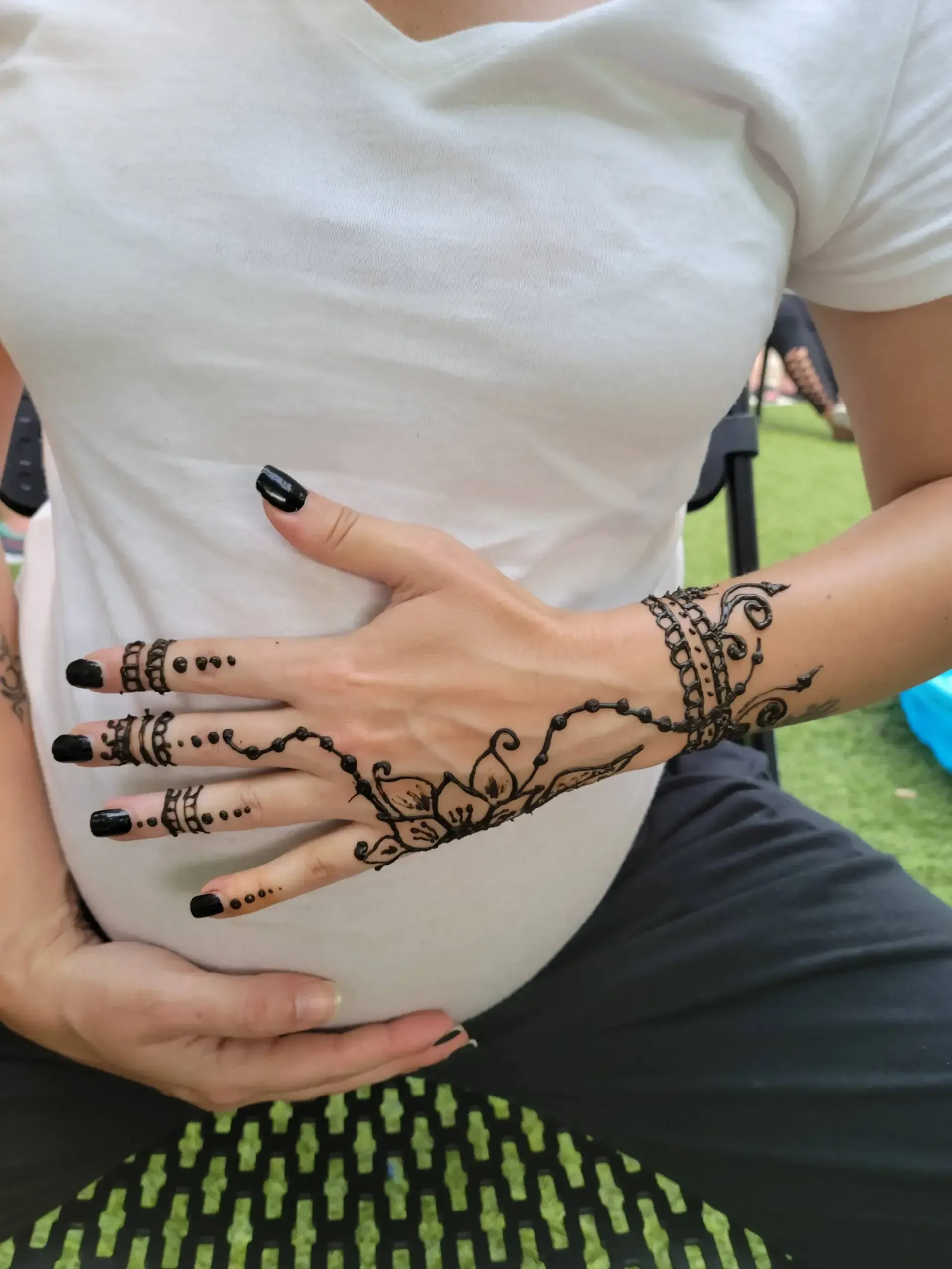 A pregnant woman has a henna tattoo on her hand