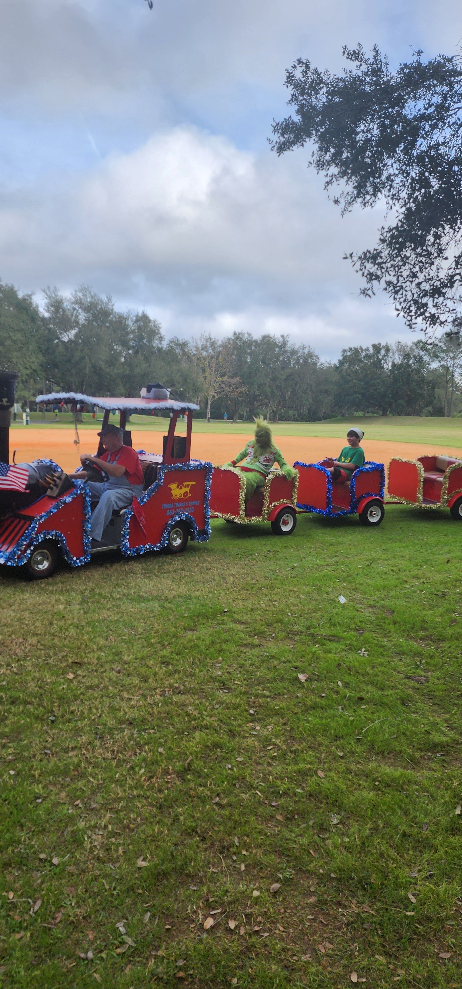 A group of children are riding a small train in a park.