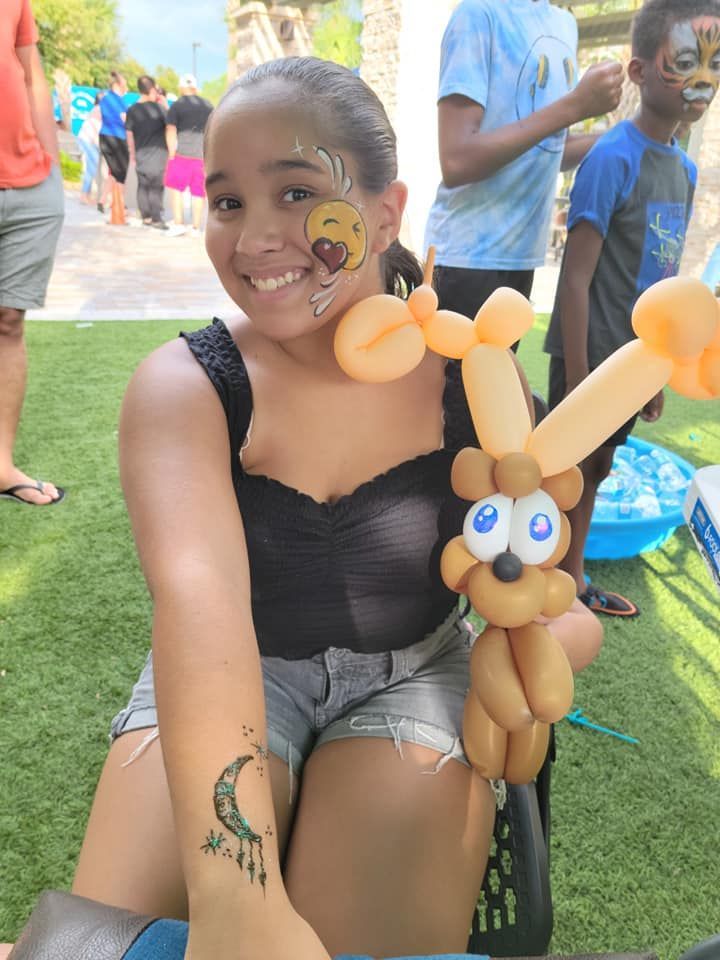 A girl with balloons on her face and a tattoo on her arm.
