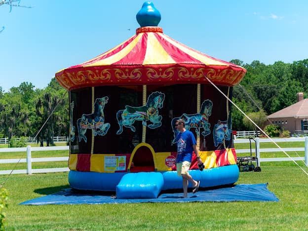 A man standing in front of an inflatable merry go round