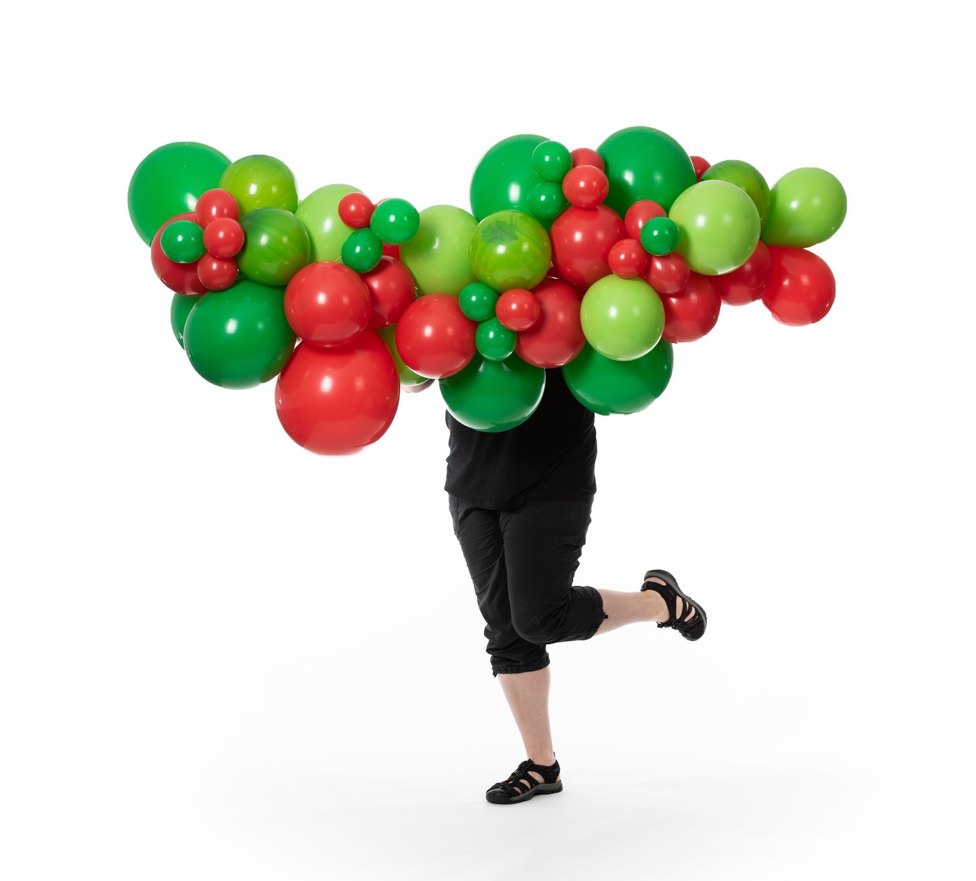 A person is holding a bunch of red and green balloons on their head