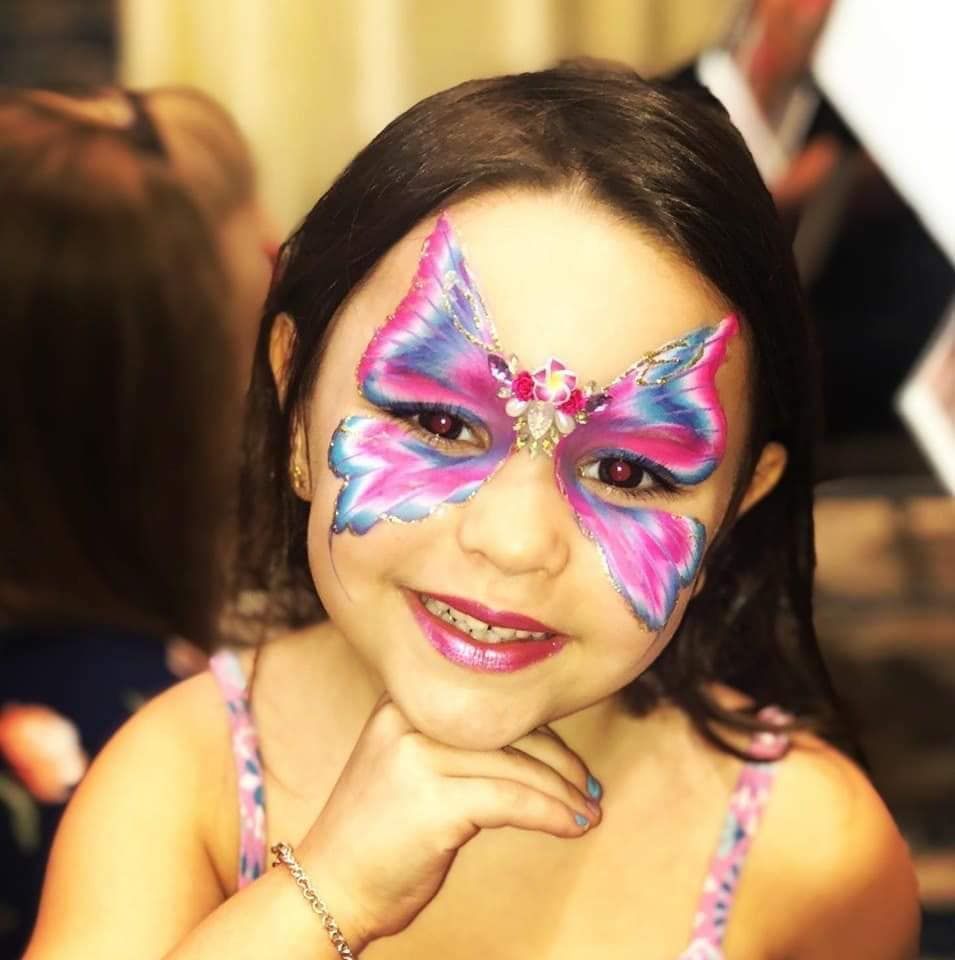 a girl with a butterfly face painted on her
