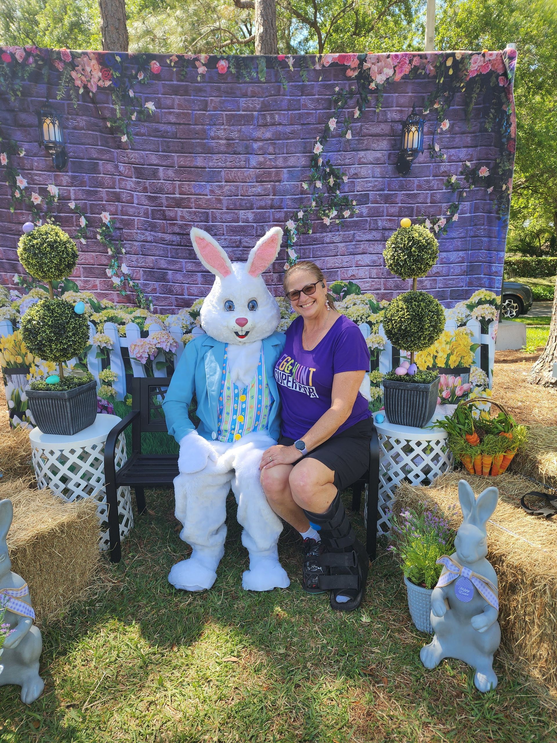 A woman is sitting next to an easter bunny on a bench.
