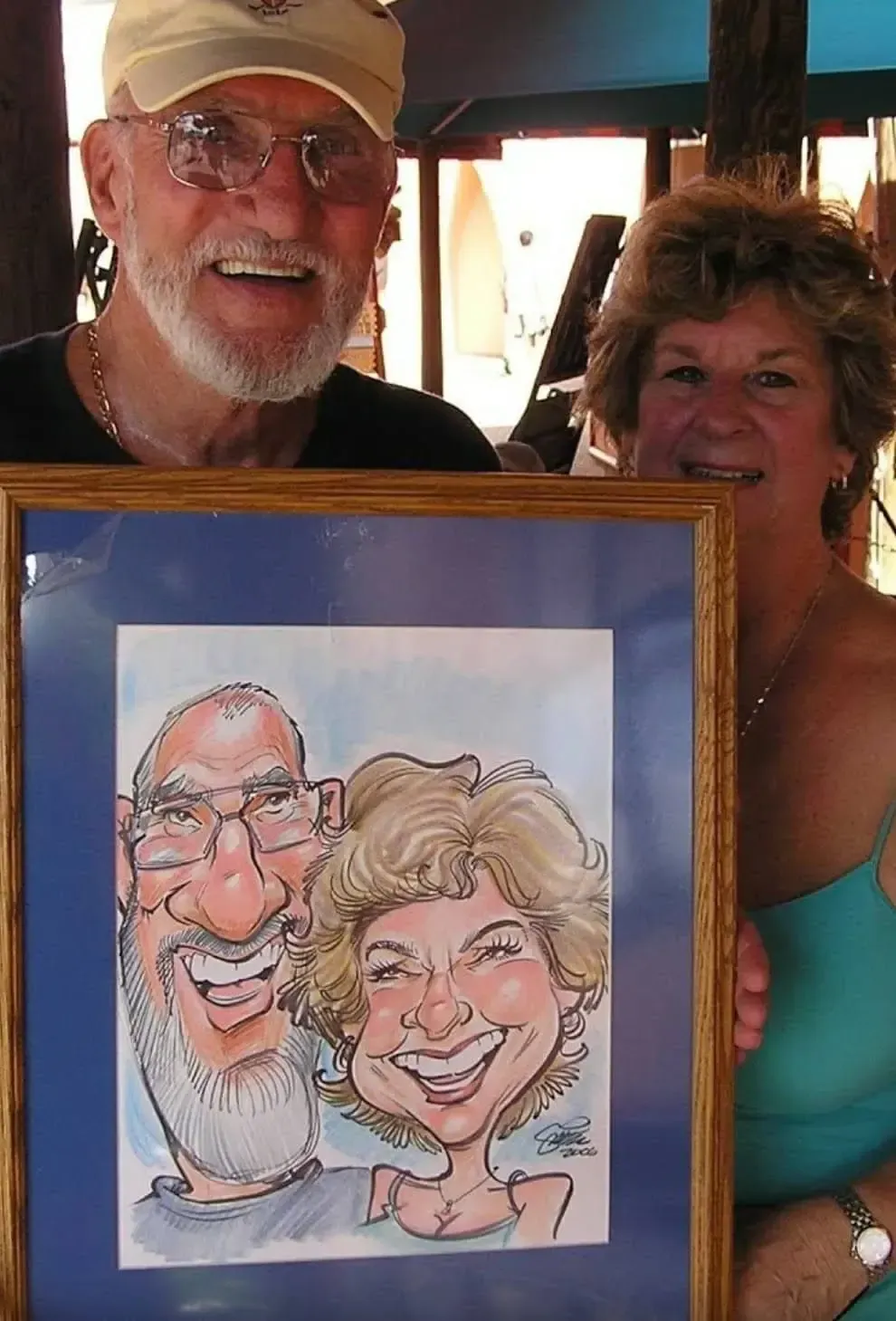 A man and a woman are holding a framed caricature of themselves