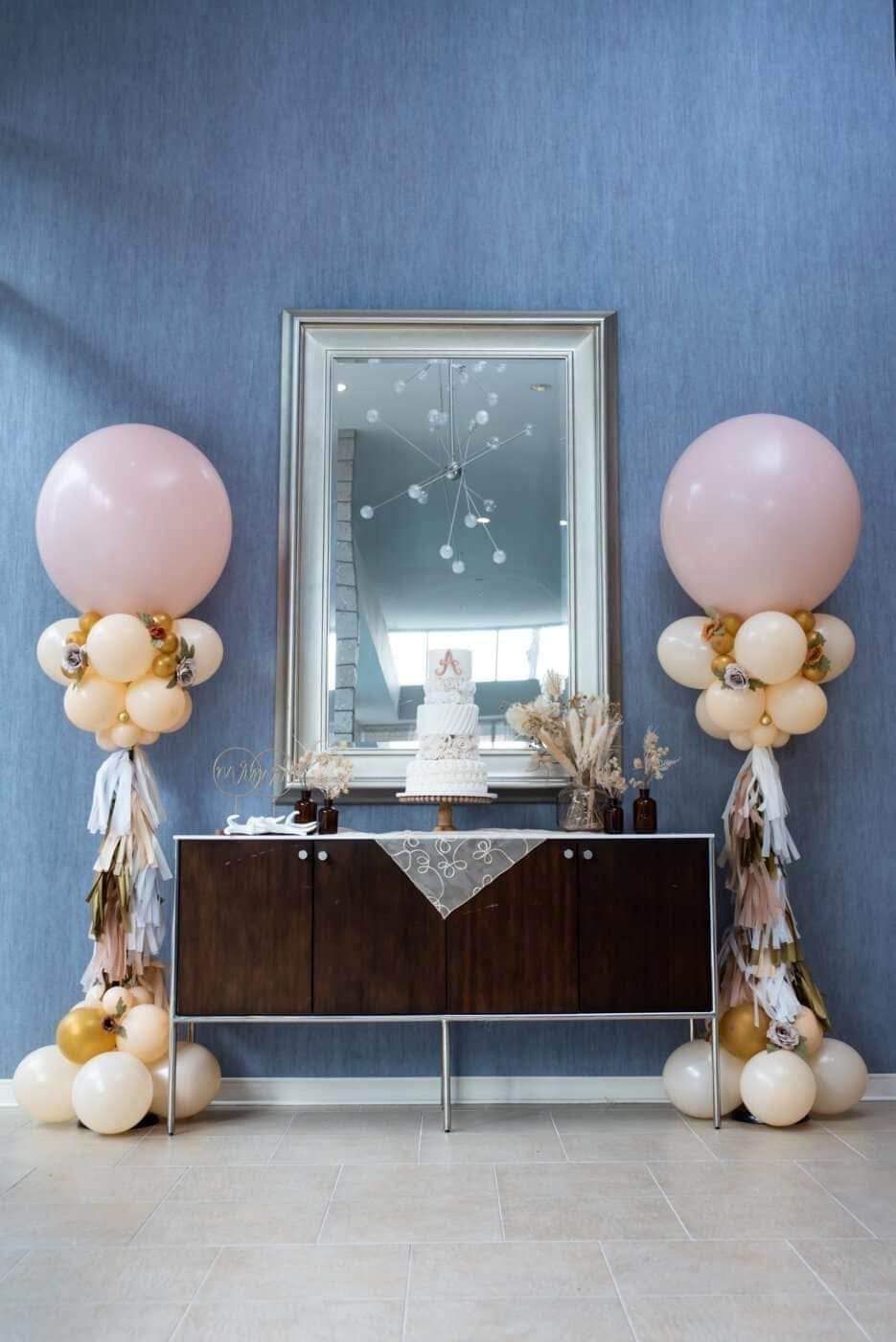 A table with balloons and a cake on it in front of a mirror.