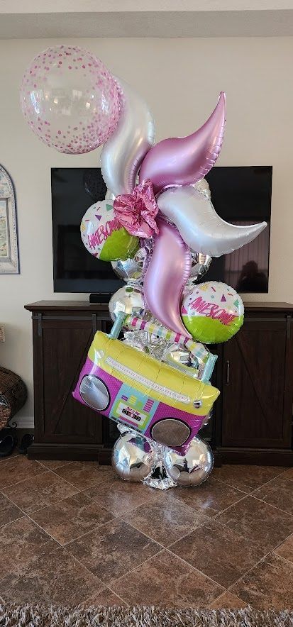 Pink unicorn balloon bouquet with a gift box and colorful balloons in a living room