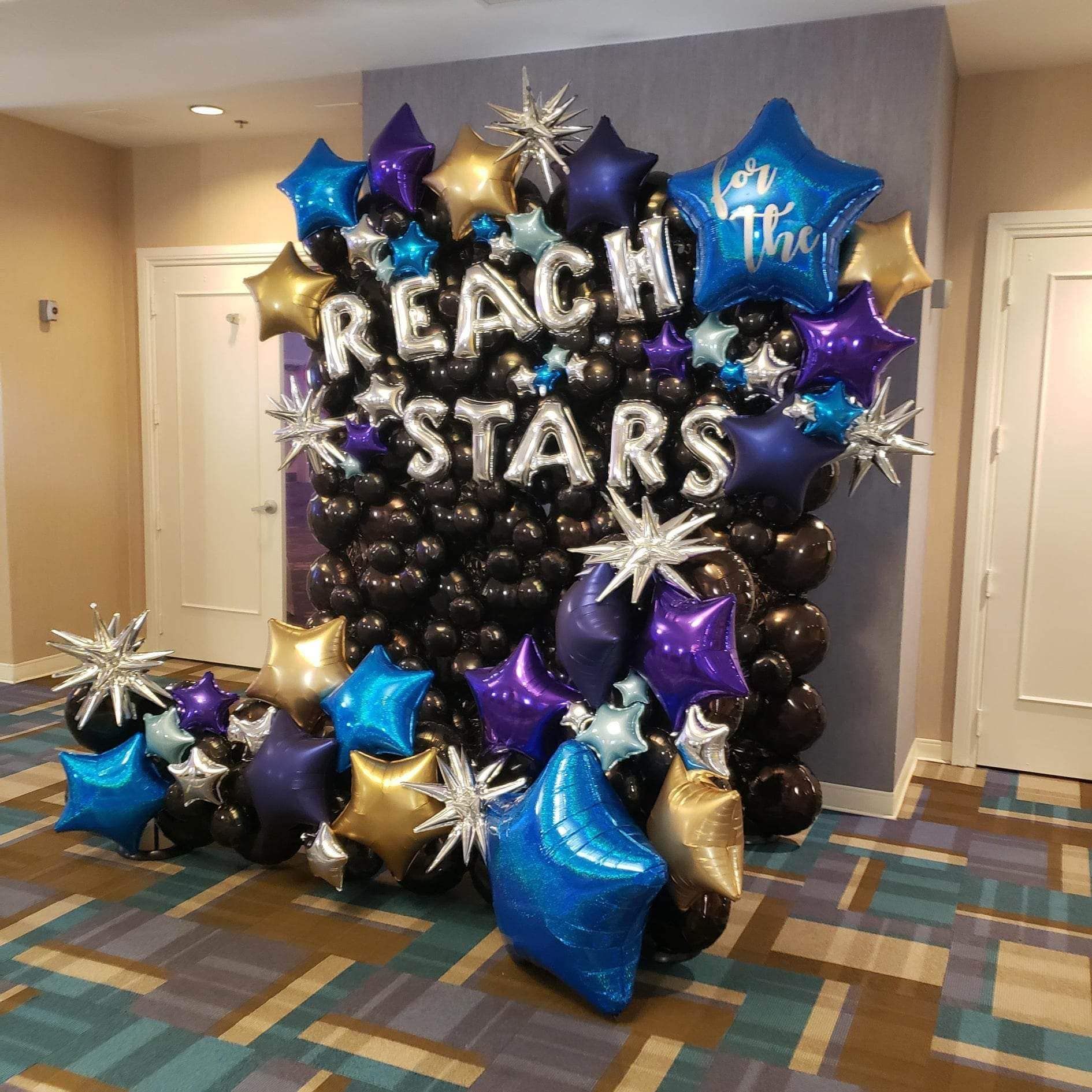 A wall of balloons with the words `` reach the stars '' written on them