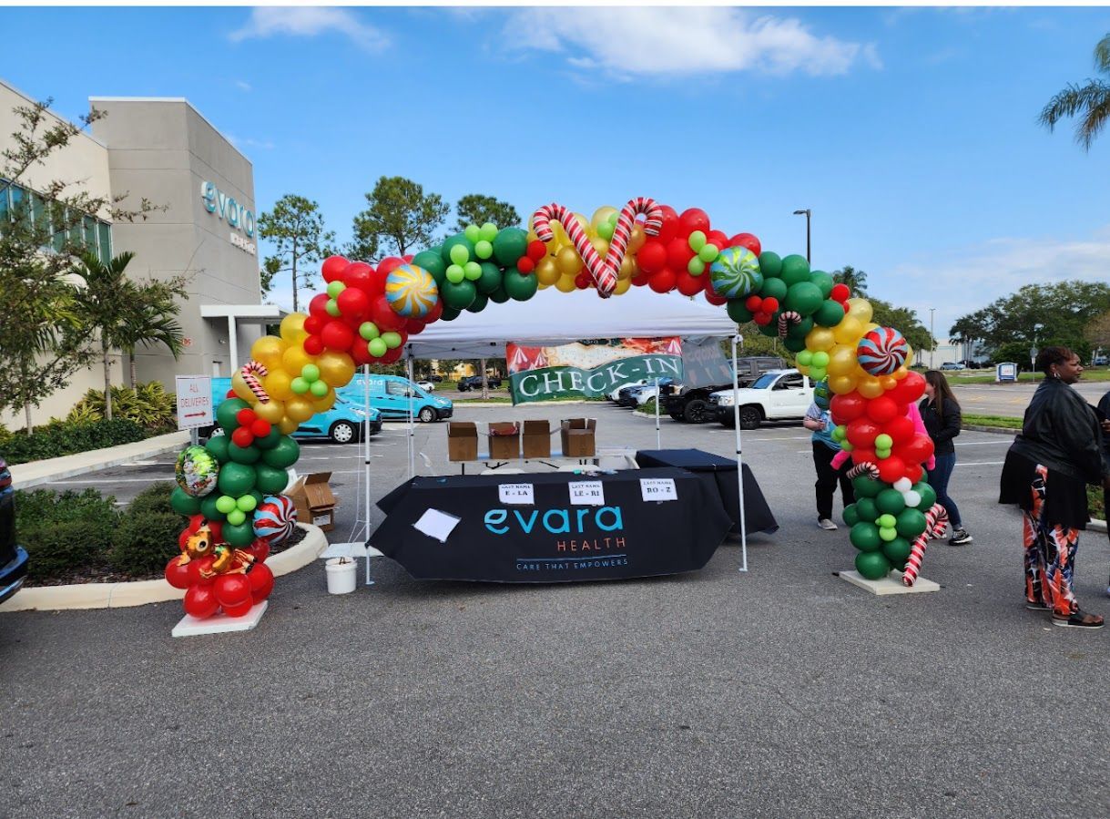 A branded Evara pop-up tent outdoors with a festive red, green, and gold balloon arch featuring candy cane decorations.
