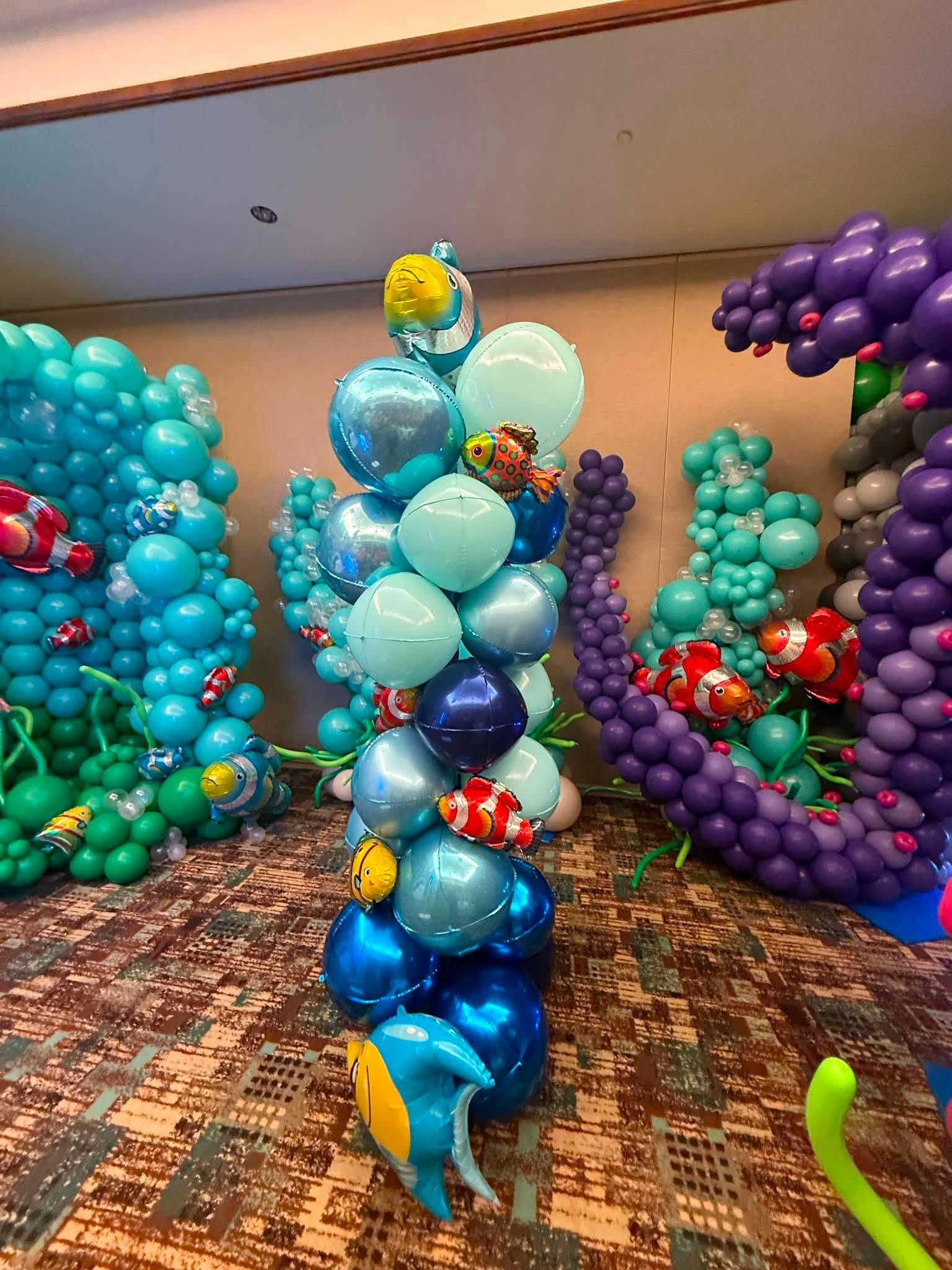 Colorful balloon sculptures resembling sea creatures in a carpeted indoor room