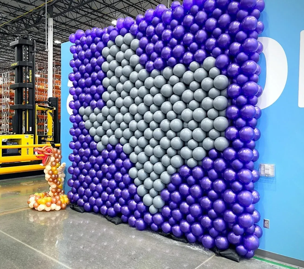 A wall of purple and grey balloons in a warehouse