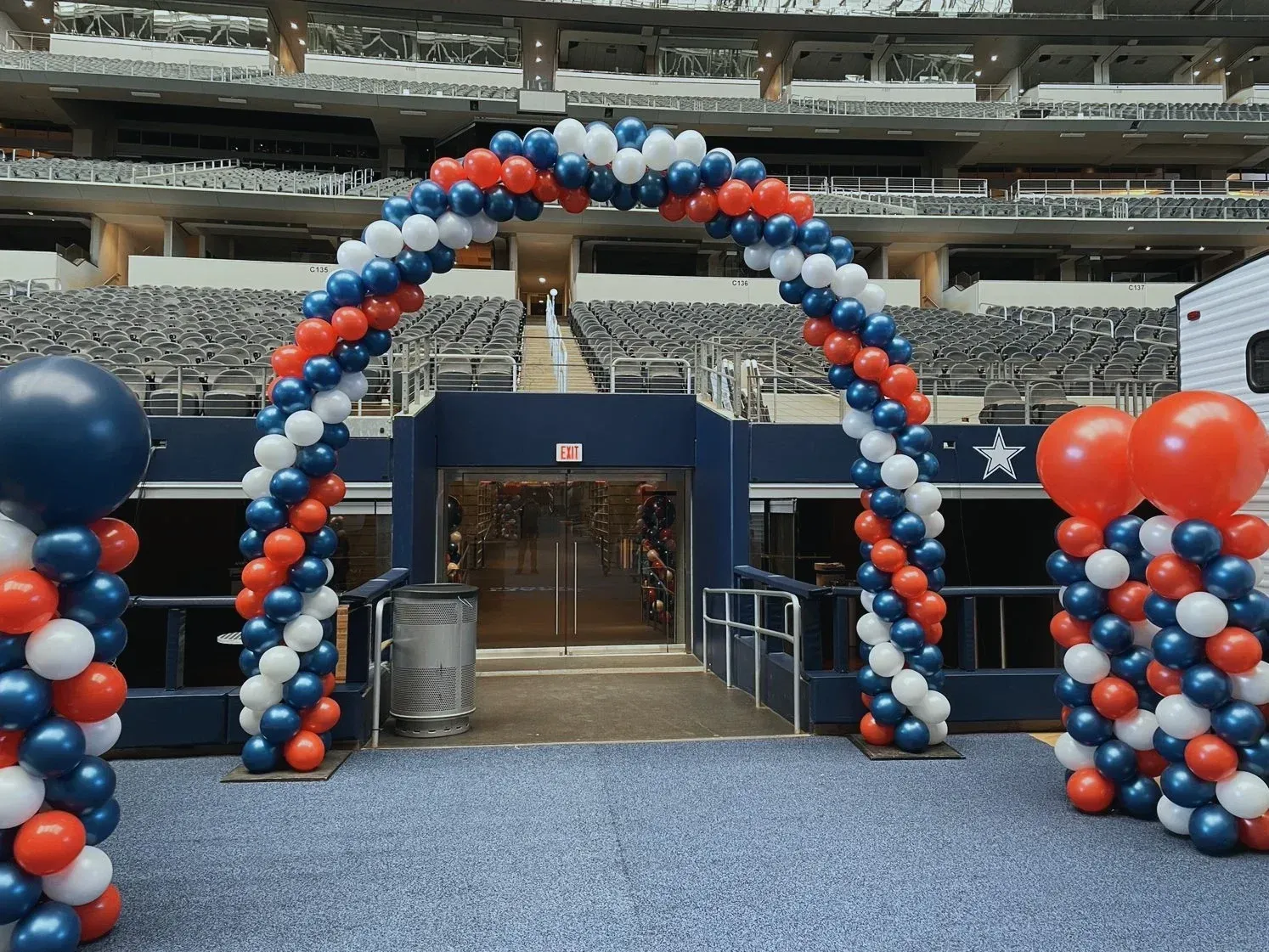 A red white and blue balloon arch in a stadium