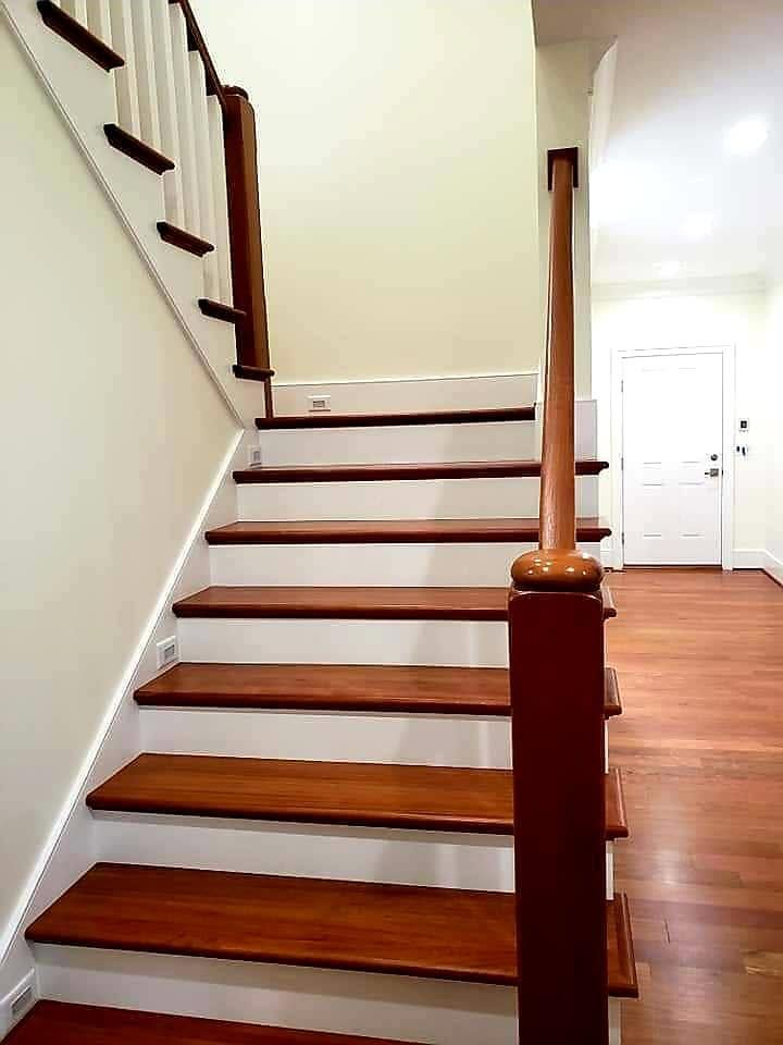 Interior staircase with dark wood steps, white walls, and hardwood floors leading to an upstairs landing