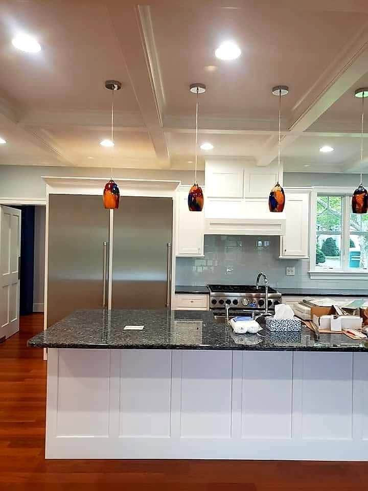 Modern kitchen with white cabinets, black island countertop, pendant lights, and stainless steel appliances