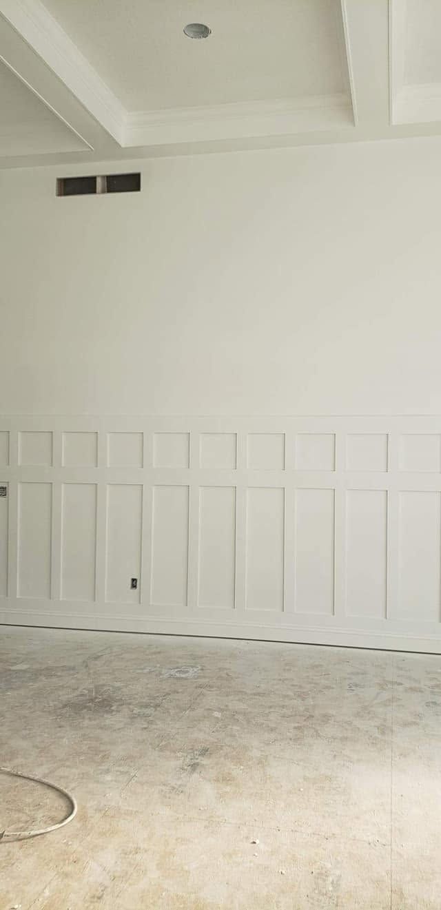 Empty white room with paneled wall and concrete floor