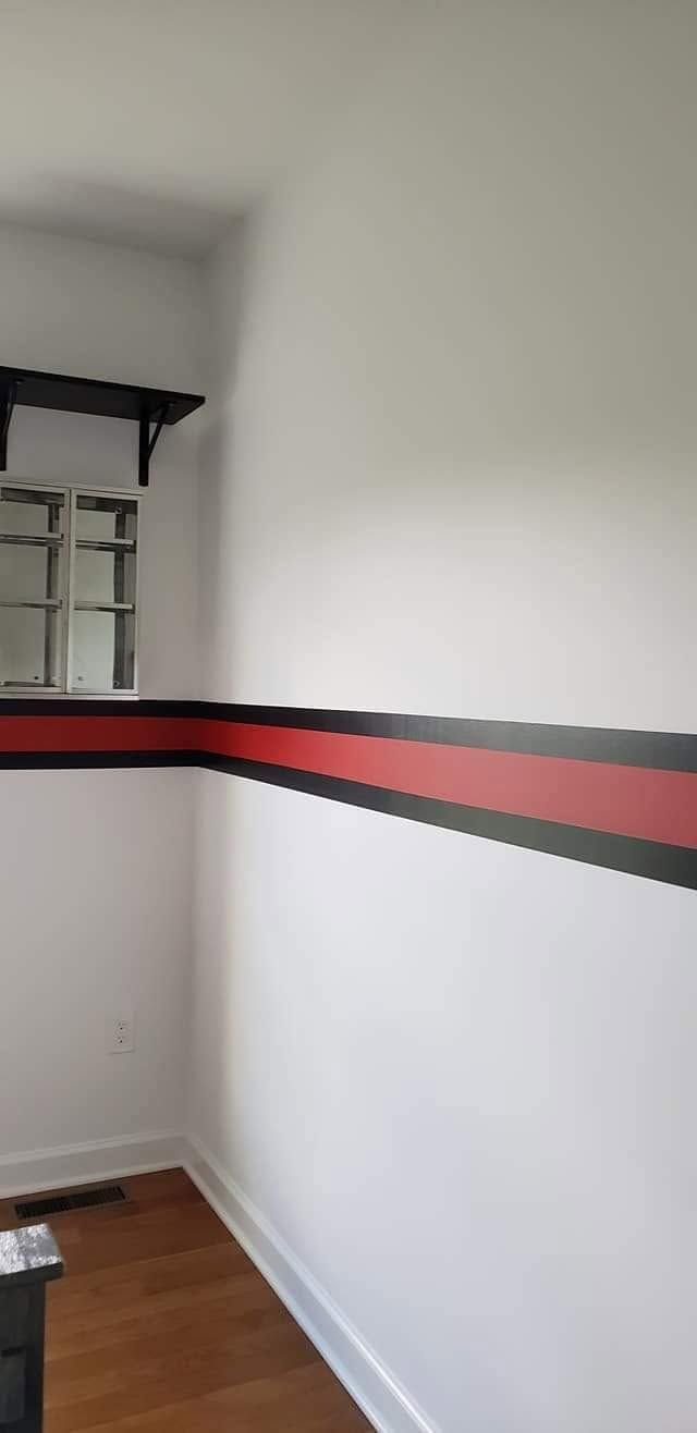 Empty white hallway with a red and black stripe on the wall and a small window at the corner