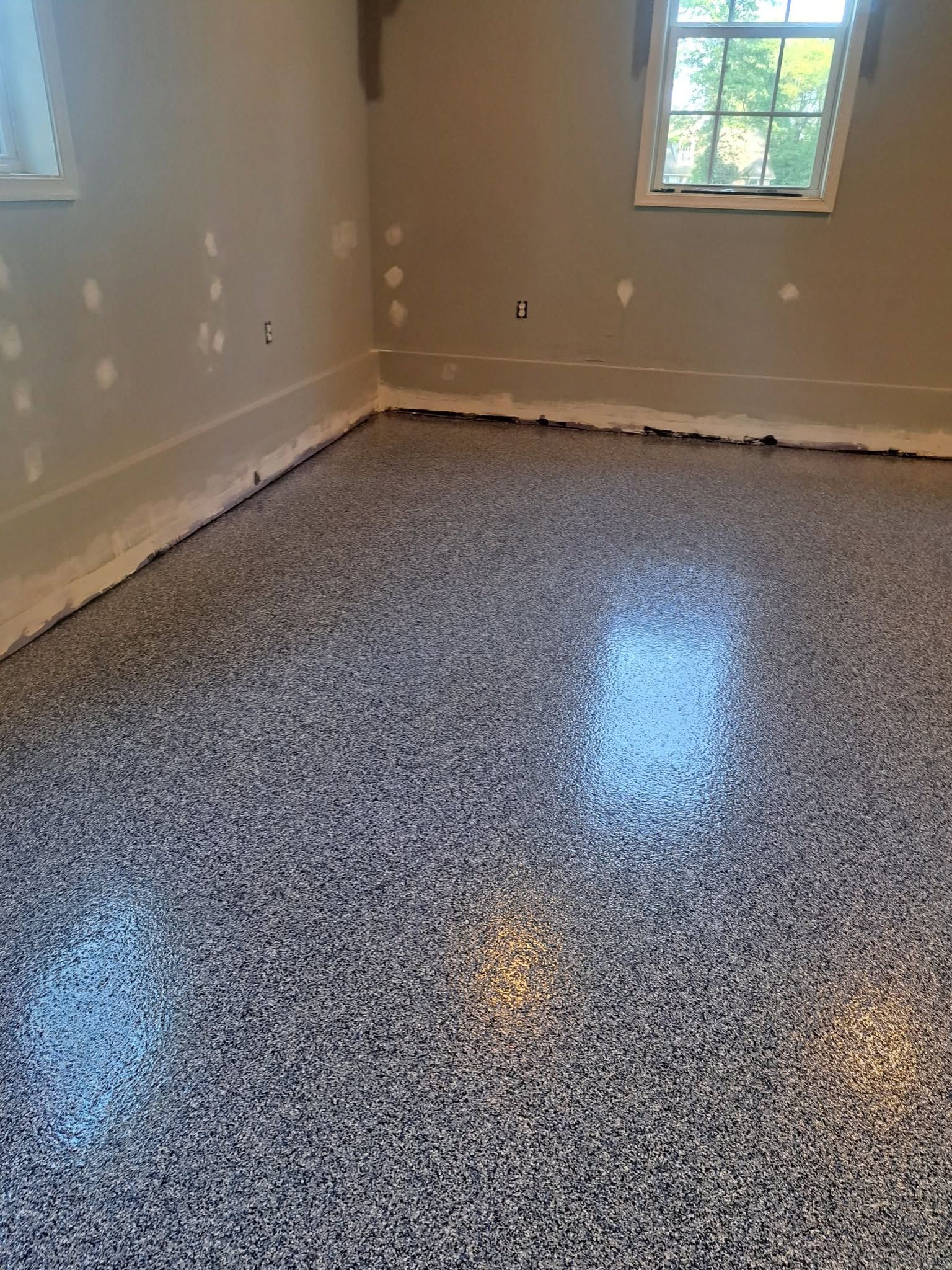 Empty room with speckled epoxy floor and a small window letting in daylight