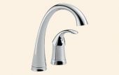 A close up of a kitchen faucet on a white background.