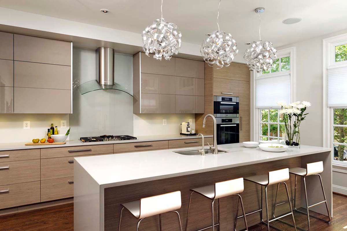 Modern bright kitchen with white island, wooden cabinets, pendant lights, and bar stools