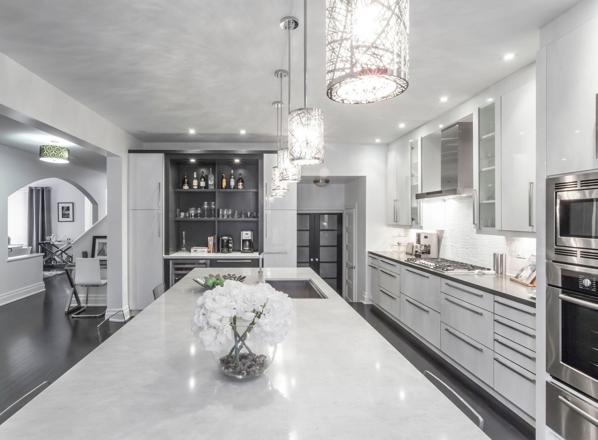 Modern white kitchen with marble island, pendant lights, and built-in appliances