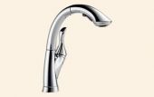 A close up of a kitchen faucet on a white background.