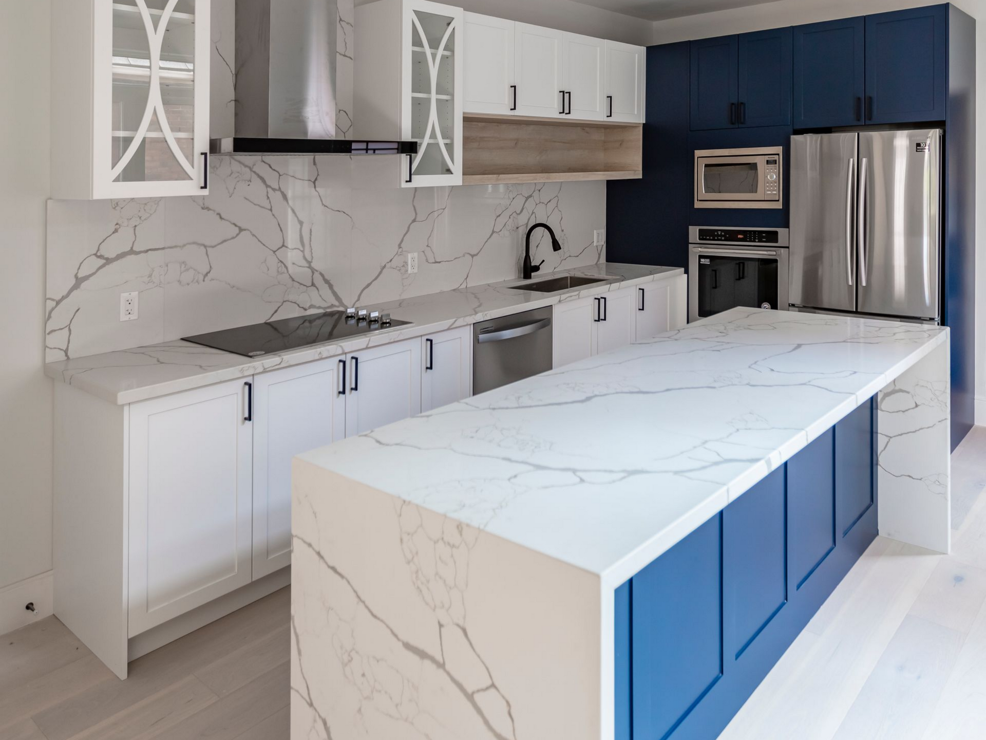 Modern kitchen with a large marble island, elegant white and navy cabinetry