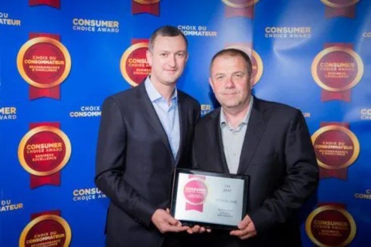 Two men are posing for a picture while holding an award