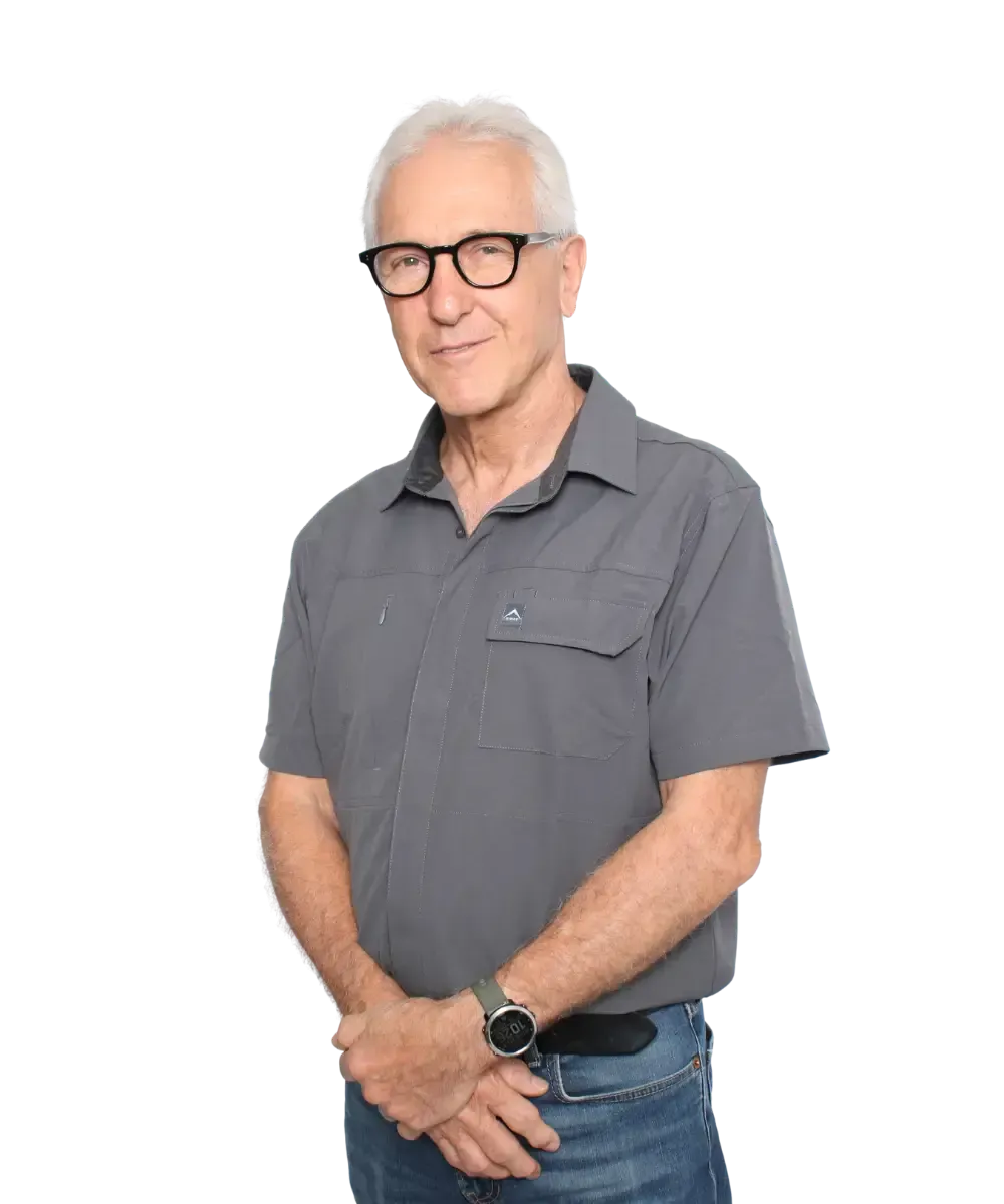 Older man in glasses wearing a gray polo shirt, standing against a white background.