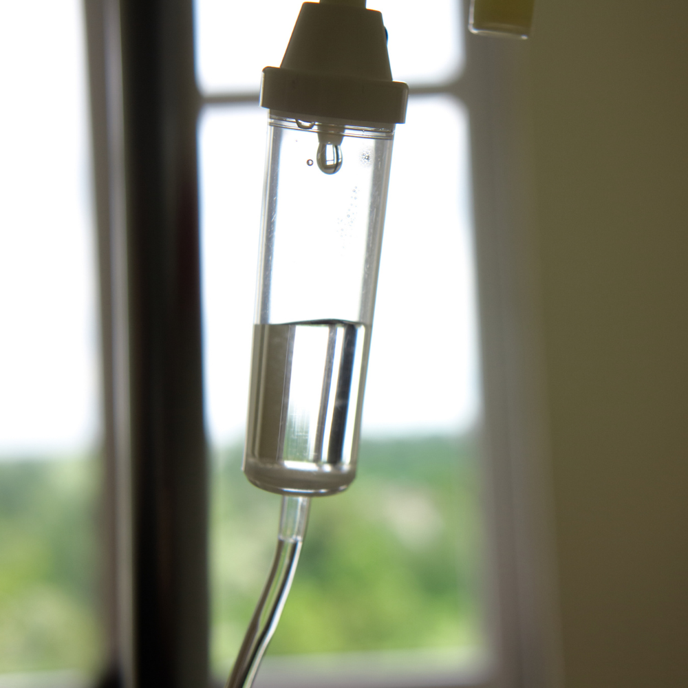 A bottle of liquid is hanging from a pole in front of a window