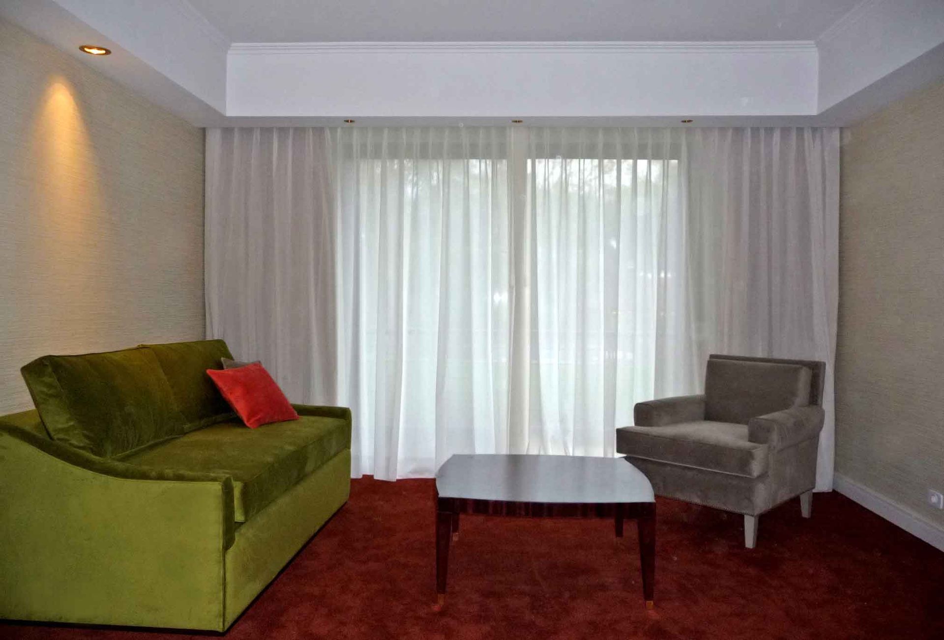 Una sala de estar con un sofá verde, una silla, una mesa de café y puertas corredizas de vidrio.