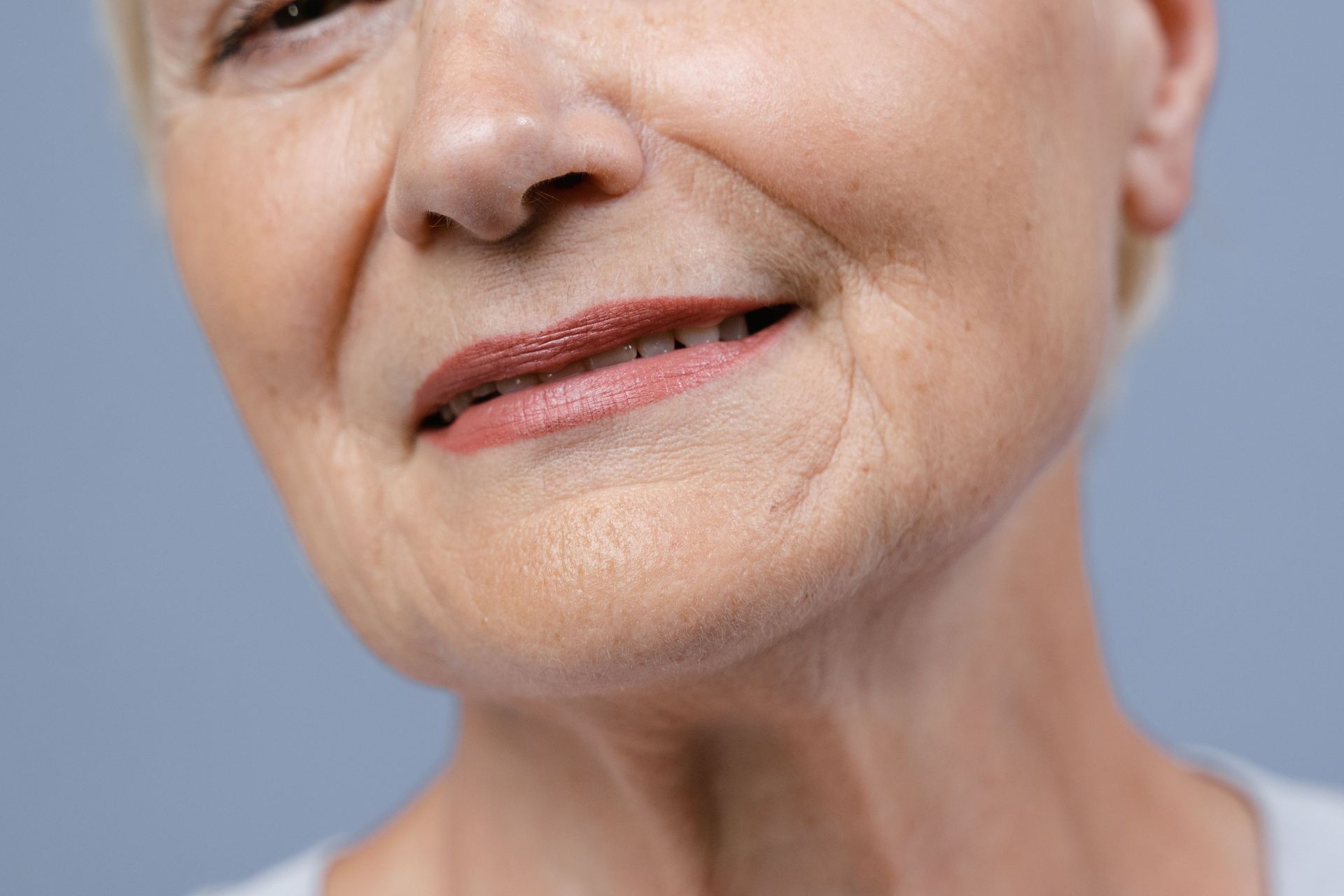 Close-up of a smiling person’s lower face against a light blue background