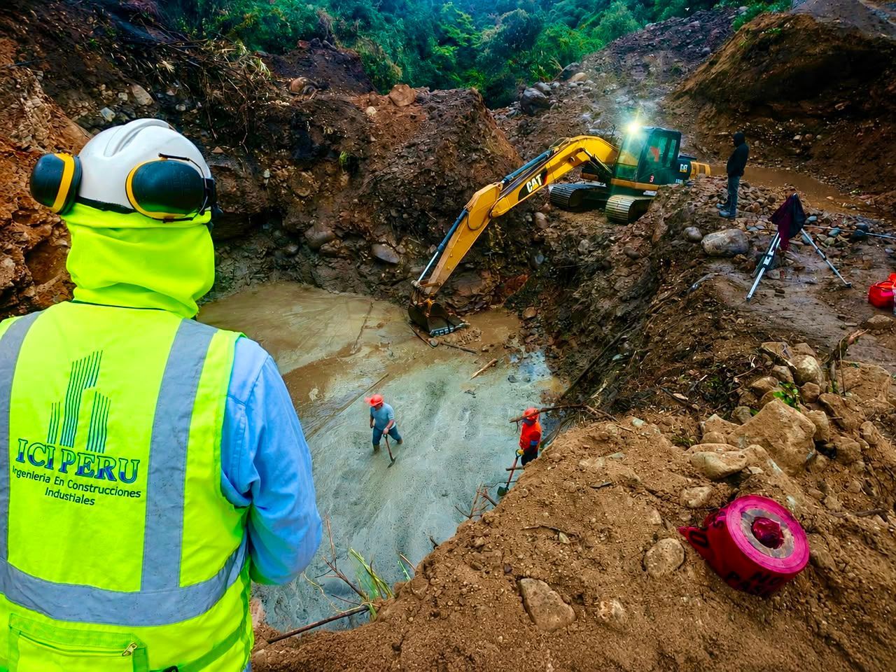 Trabajadores y una excavadora en una fosa de excavación fangosa