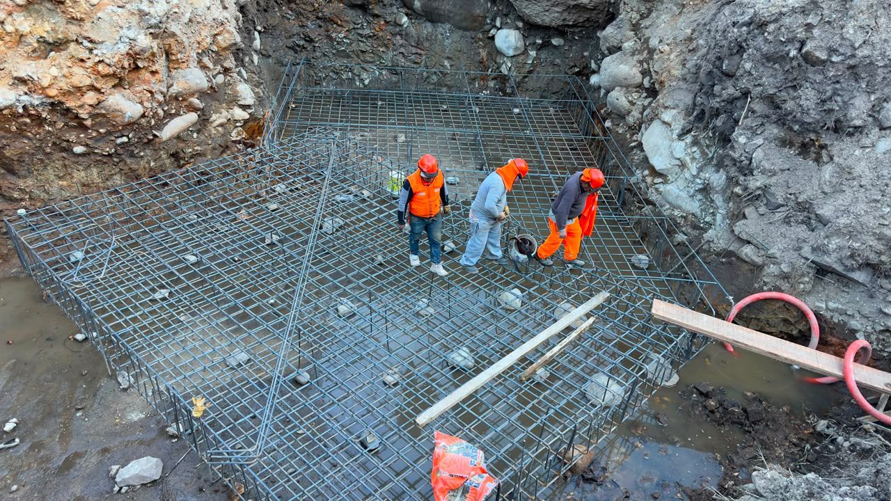 Trabajadores con ropa de color naranja permanecen de pie sobre barras