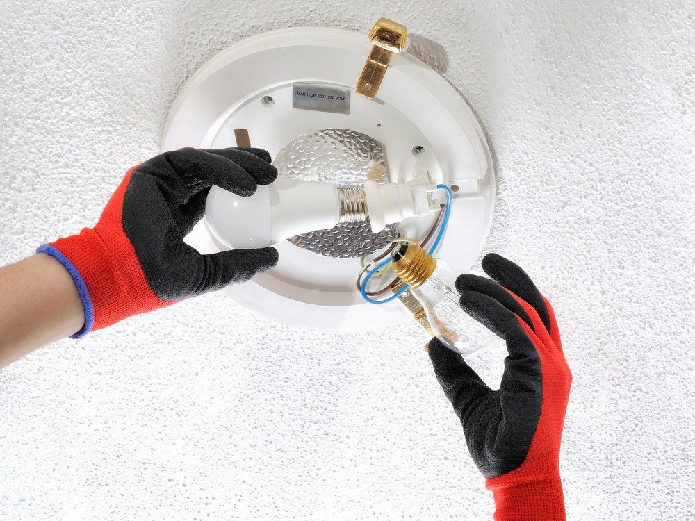 Electrician Replaces Light Bulb — Electricians In Bundaberg, QLD
