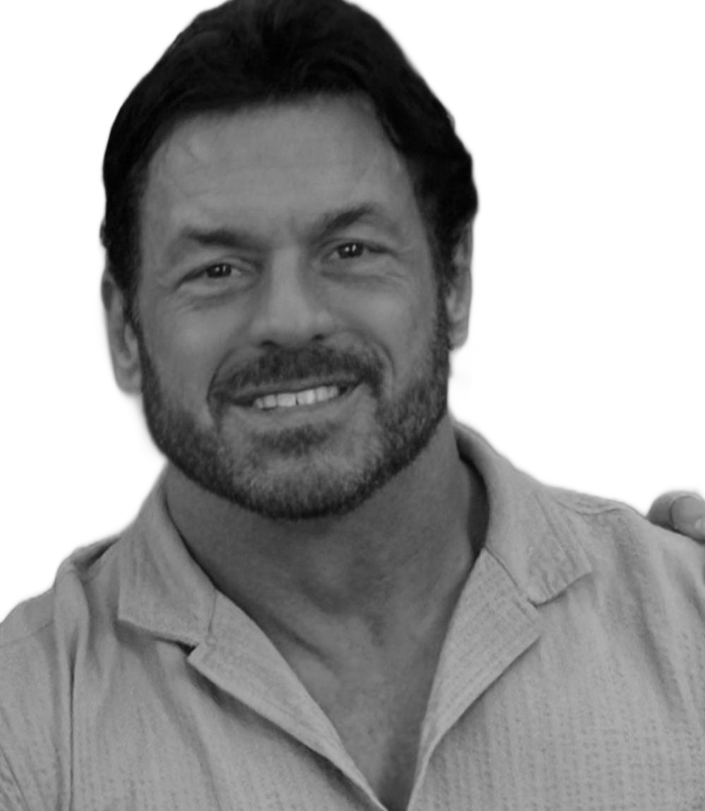 Man smiling, wearing a suit and tie, against a white background.