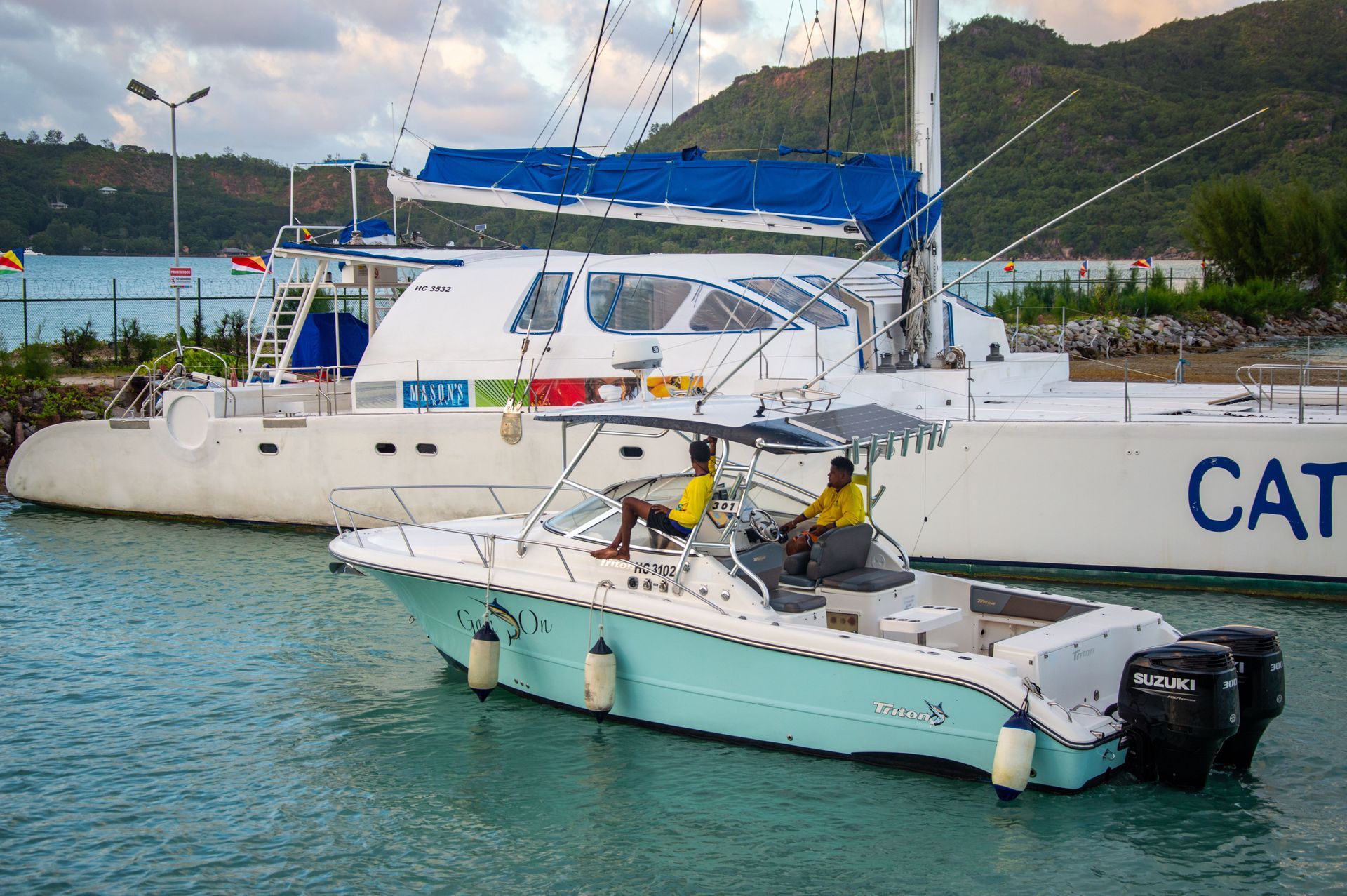 Catamaran and fishing boat docked in marina.