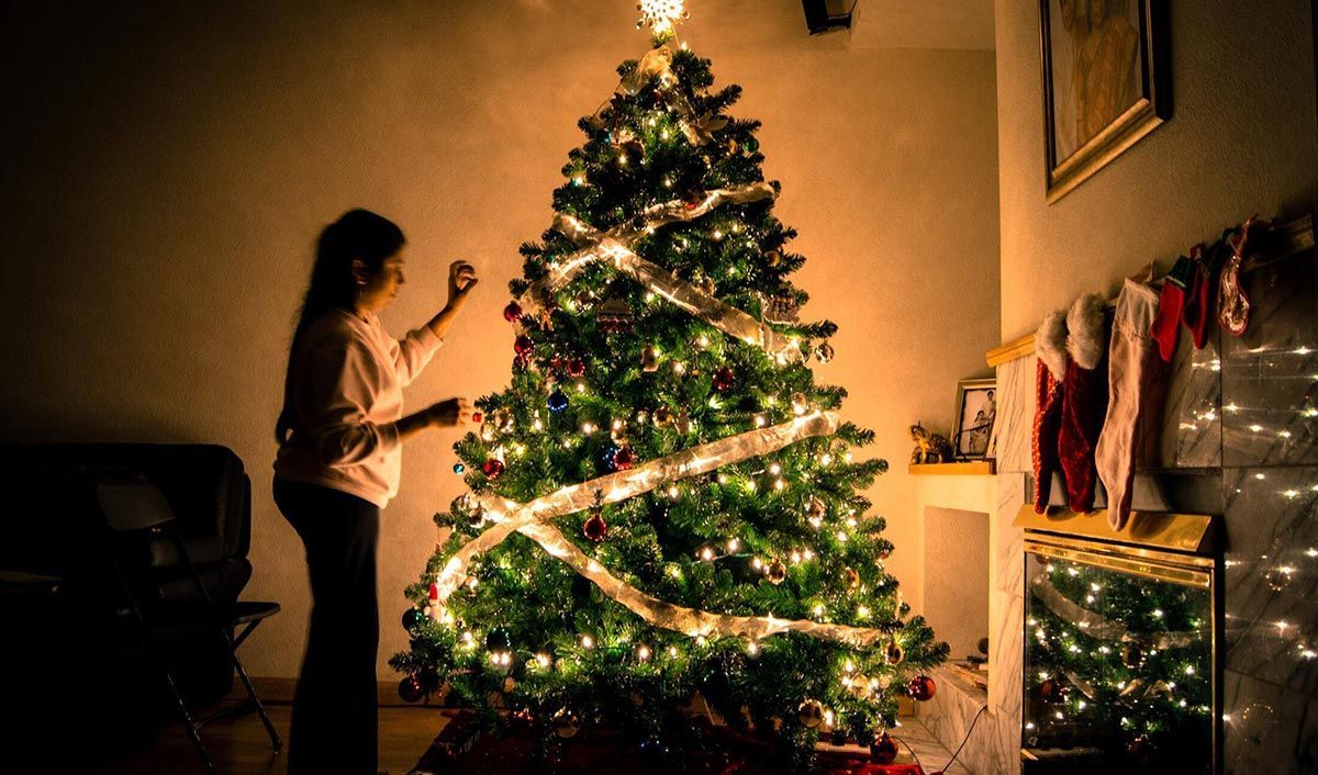 woman decorating a christmas tree