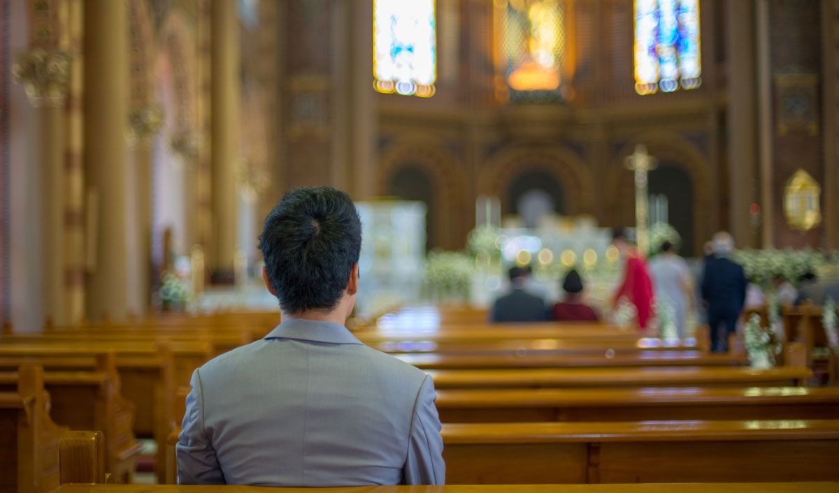 Person sitting in the pews at a funeral in a beautiful church