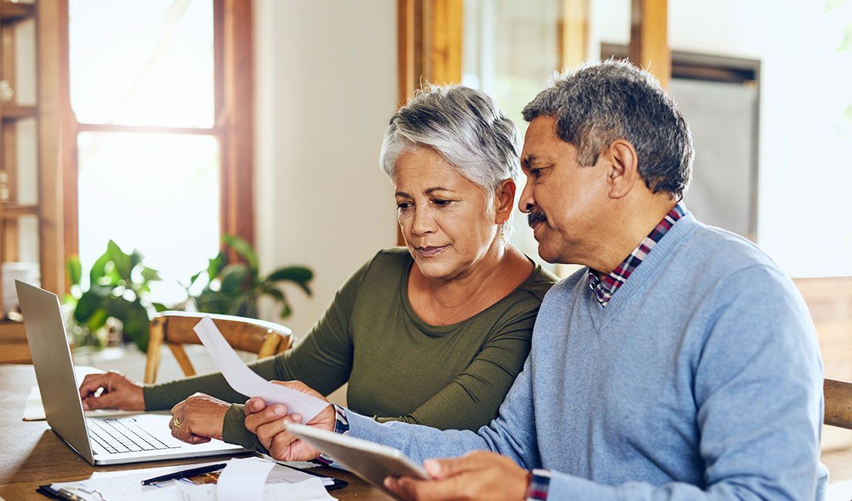 Hispanic couple looks at papers with a laptop