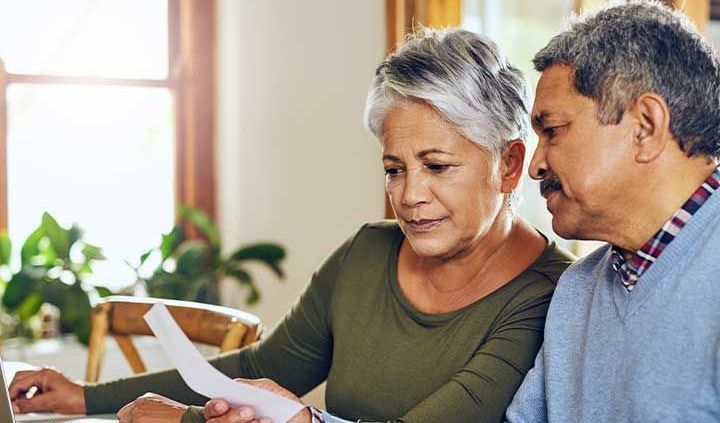 Hispanic couple looks at papers with a laptop